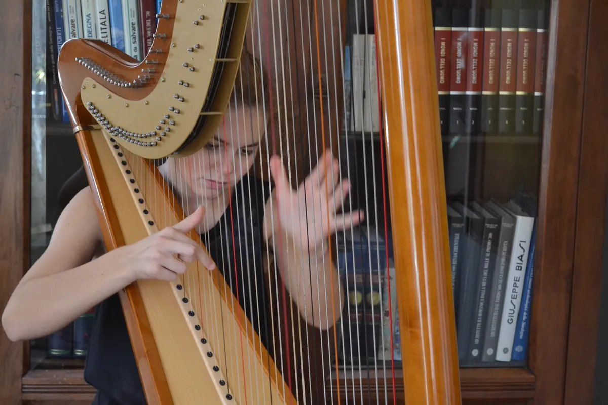 Eleonora Congiu's hands lifting from the harp strings at the end of a phrase