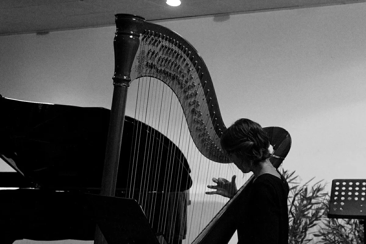 A pedal harp and a grand piano in low light before a recording session