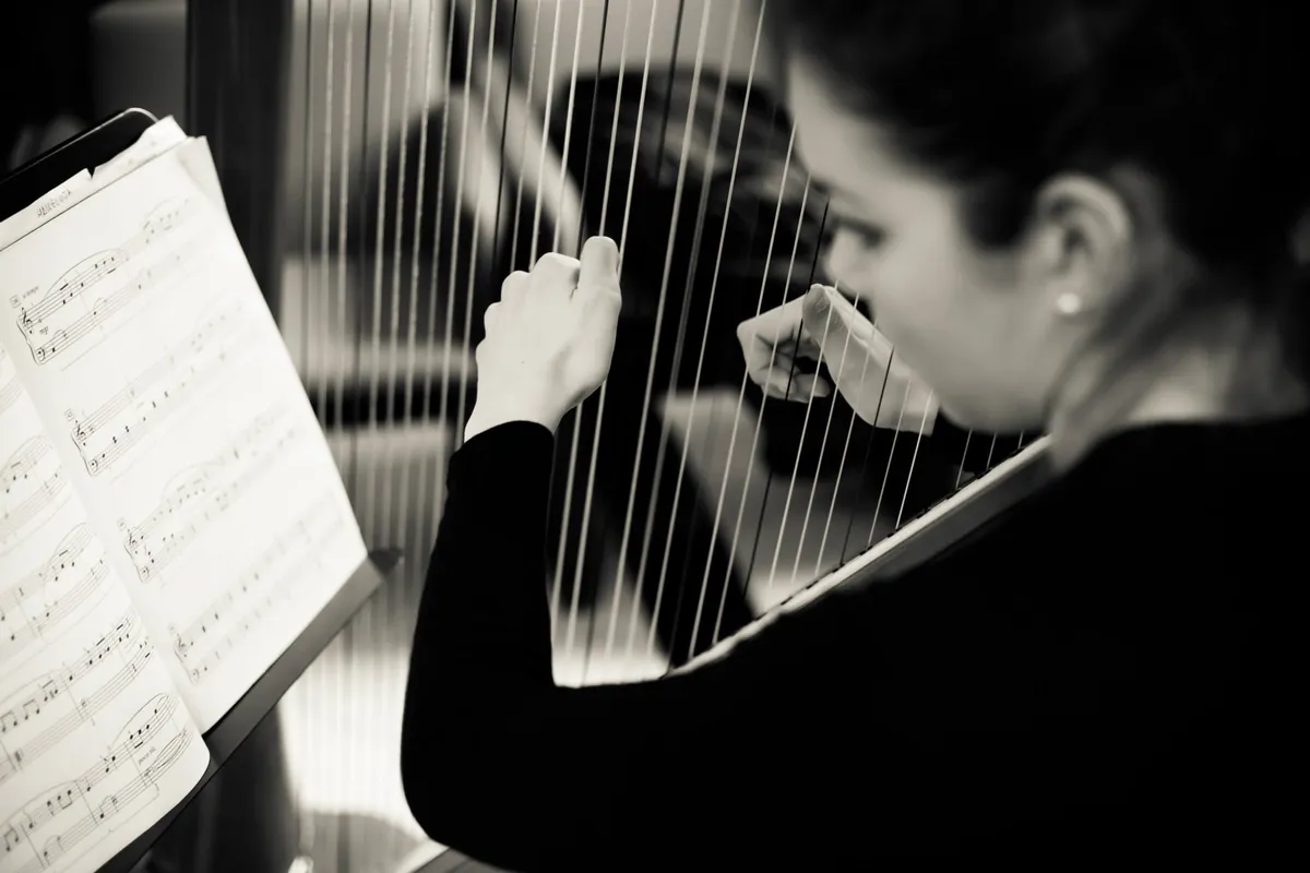Eleonora Congiu reading from the score at the pedal harp, in black and white